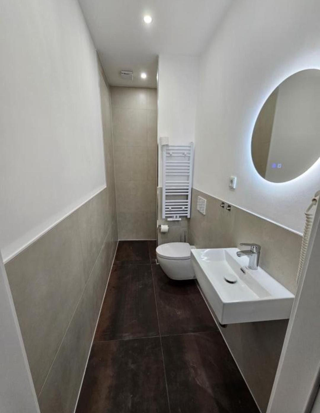 Modernisiertes Badezimmer mit Waschtisch, WC und rundem Spiegel
